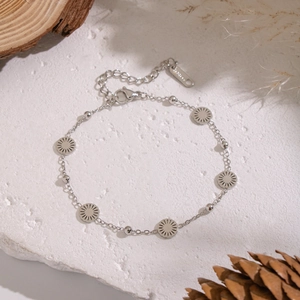 Detailed view of silver sunburst pendant bracelet on a natural stone surface