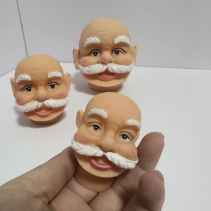 Close-up of mini 3D vinyl Santa Claus heads for DIY Christmas crafts held in hand