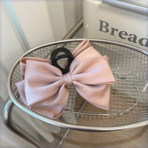 Detail of dusty pink satin double-layered bow hair claw with premium silk texture