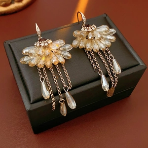 Detailed close-up of champagne crystal fan fringe earrings on a black jewelry box display