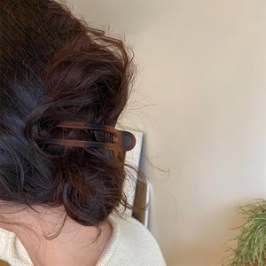 Brown tortoiseshell hair claw clip securing a bun hairstyle in a soft natural setting