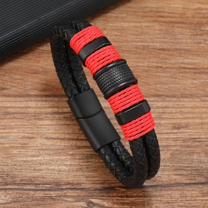Close-up of black and red braided leather bracelet with magnetic clasp on wood