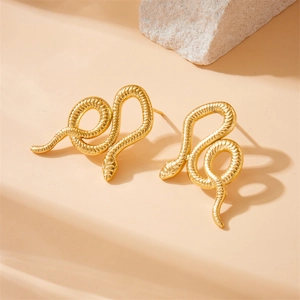 Vintage gold snake earrings with striped texture on a minimalist stone display