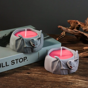 Gothic bat candle holder in grey and red tones on a rustic wooden table detail