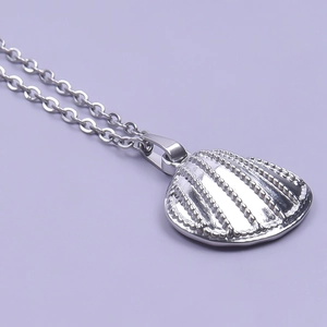 Detailed close-up of a silver shell-shaped pendant on a minimalist necklace