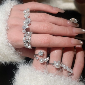 Detail of elegant pearl and zircon open rings with star and cat ear motifs on hand