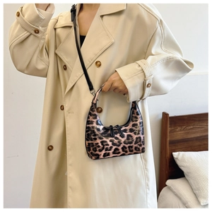 Close-up of leopard print patent leather bag with silver buckle worn with a beige coat