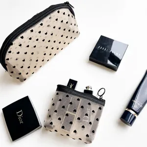 Detail view of heart pattern mesh makeup bag set with premium cosmetics on white surface