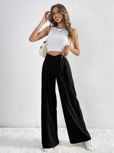 Detail of high waisted V-shaped waistband and pleated texture on black wide leg trousers