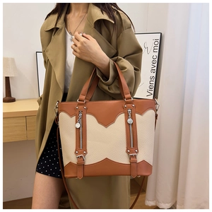Detail of color-block tote bag with dual zippers and premium pebble leather texture