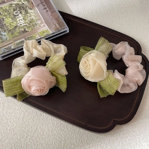 Elegant handmade organza rose scrunchies in pink and beige on a wooden tray
