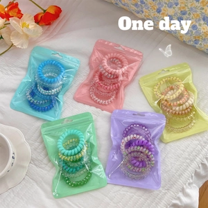 Detail of gradient spiral hair ties in colorful individual sets on a white fabric background