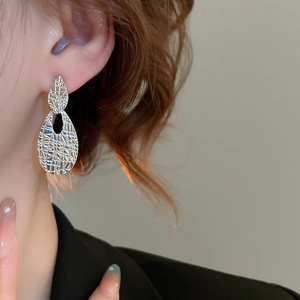 Detail of silver drop earrings with hammered texture on model showing the hollow design