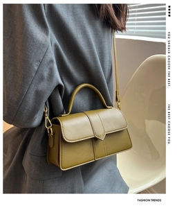 Detail of olive green structured handbag featuring gold hardware and a V-cut flap design