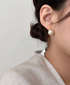 Close-up of gold plated silver earrings with white pearl inlay worn by a model