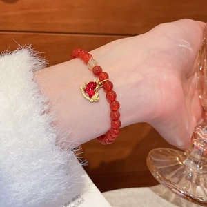 Détail du bracelet en perles d'agate rouge avec un pendentif cheval porté par un modèle