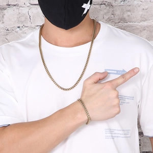 Close-up of gold titanium steel curb chain necklace and bracelet set on a male model