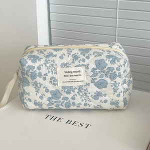 Detailed close-up of blue floral quilted cosmetic bag with metal zipper and fabric handle