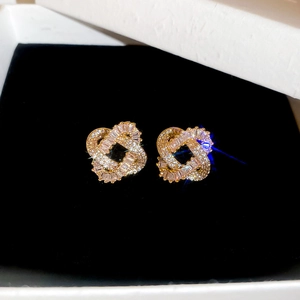 Macro shot of gold-plated twisted stud earrings with white zircon in a black box