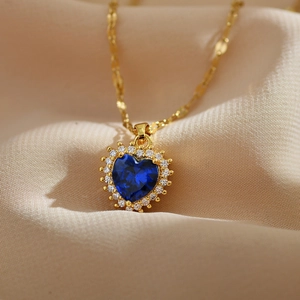 Elegant heart-shaped blue sapphire pendant necklace with gold chain on silk fabric