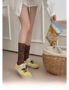 Close-up of brown knit leg warmers with logo label and vintage sneakers