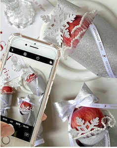 Macro view of Christmas apple gift wrapped in silver glitter fabric with snowflake charm