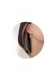 Détail de boucles d'oreilles ovales plaquées or 18K avec perles rondes blanches