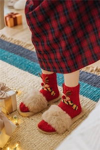 Detail of red Christmas coral fleece socks and plush slippers with reindeer patterns