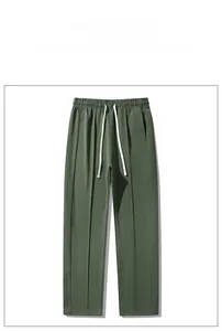 Detail of dark green casual pants showing elastic drawstring waist and vertical pleats