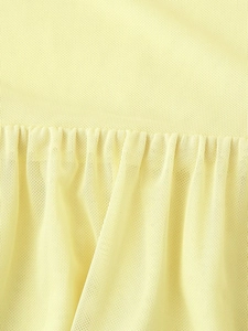 Detailed macro view of yellow mesh fabric texture and pleated stitching on the elegant dress