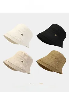 Detail of four-color bubble textured bucket hats with metal logo on light grey background