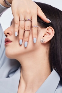 Close-up of elegant S925 silver rings with colorful zircon and floral stud earrings on model