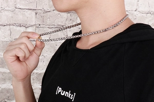 Close-up of polished silver box chain necklace worn by male model on black hoodie