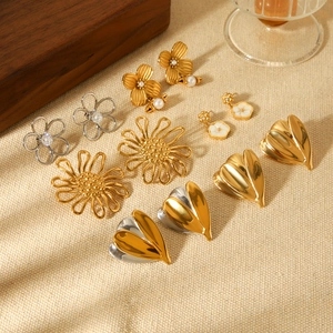 Flat lay of multiple flower and heart stud earrings in gold and silver finish
