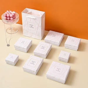 White marble jewelry gift box set with gold lines and matching paper gift bags