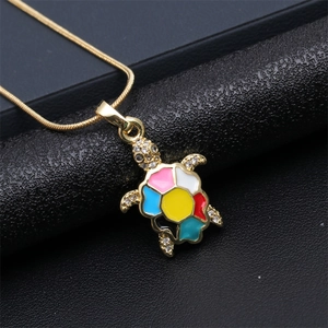 Macro detail of gold sea turtle pendant with colorful enamel and micro zircon inlay