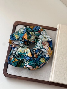 Artistic abstract print fabric scrunchie with blue and orange floral pattern on tray