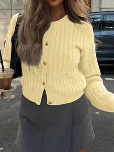 Detail of light yellow cable-knit cardigan with classic button closure and textured pattern