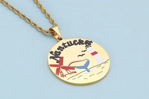 Close-up of gold Nantucket pendant with enamel nautical motifs on a blue background