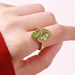 Detailed view of a gold-finish ring featuring a green marquise stone and bow design