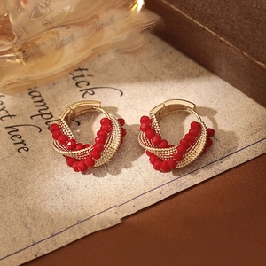 Macro view of twisted gold wire and red crystal beads on the stylish hoop earrings