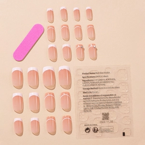White French tip press-on nails set with rhinestones and adhesive tabs on beige background
