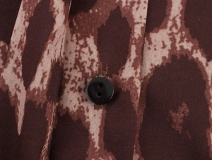 Close-up of leopard print fabric texture and a black button on the loose two-piece set