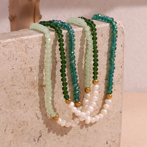 Macro shot of green faceted crystal beads and freshwater pearls on a gold-beaded necklace