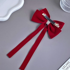 Close-up of red velvet bow hair clip with luxury rhinestone tassel and metal spring clip