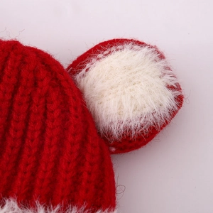 Close-up of red winter knit hat with white faux fur ears and detailed thermal texture