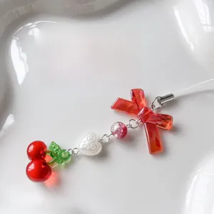 Close-up of a cute red cherry and bow charm with pink beads on a white heart plate