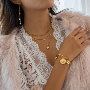 Gros plan d'un ensemble de bijoux en acier doré 18K avec pendentifs cœur et pièce