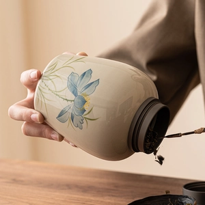 Elegant cream ceramic tea canister with hand-painted blue lotus flower and zen aesthetic