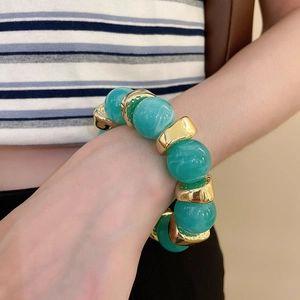 Detailed view of mint green marble acrylic beads and irregular gold metal spacer charms